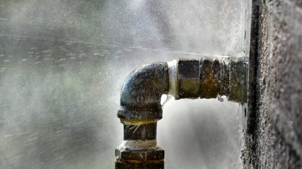 close-up of burst pipe spraying water